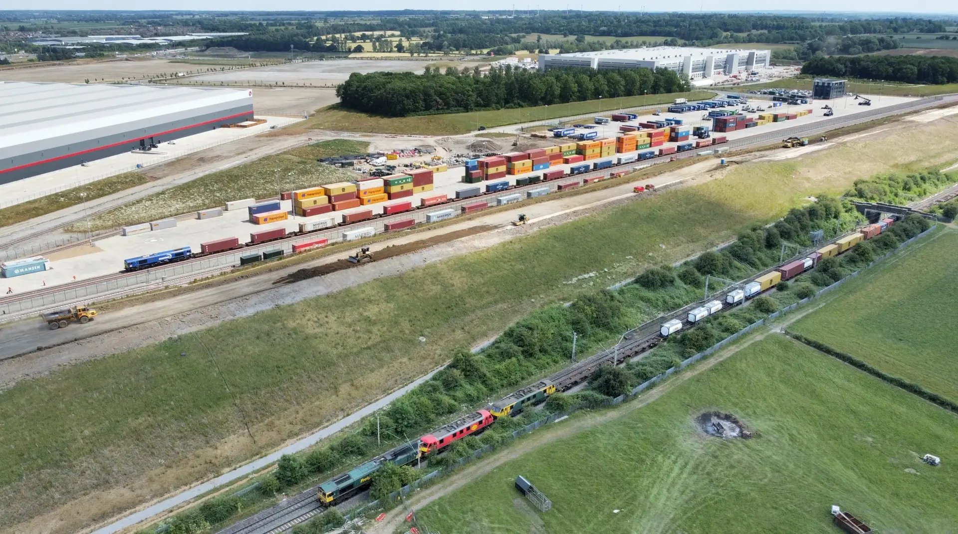 Double-stacked intermodal container train crossing open country under a wide sky.
